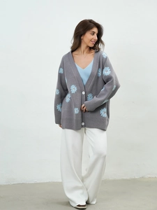 Detail of grey oversized knit cardigan with light blue flower embroidery and buttons