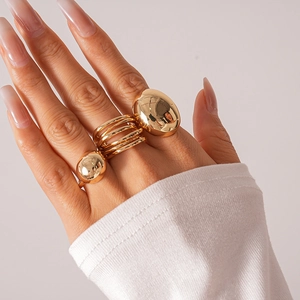 Detailed close-up of a three-piece gold metal geometric ring set worn on a model hand