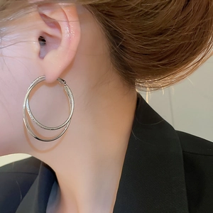 Detail of silver double layered hoop earrings with smooth and textured finish on model
