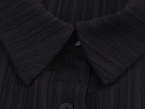 Détail du col boutonné de la robe noire sans manches avec texture en maille côtelée