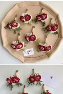 Close-up of handmade red rose boutonnieres with natural twine wrap and green leaves