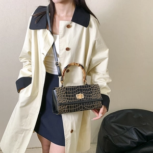 Detail of black crocodile pattern handbag with bamboo handle and gold twist lock