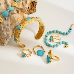 Vintage turquoise jewelry set featuring a hammered gold cuff, beaded bracelet and rings