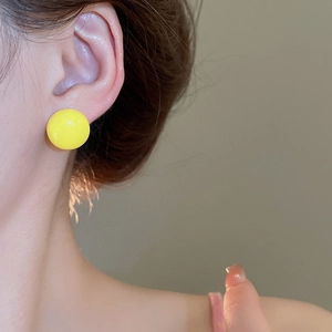 Close-up of bright yellow round ball earrings on model for a minimalist style