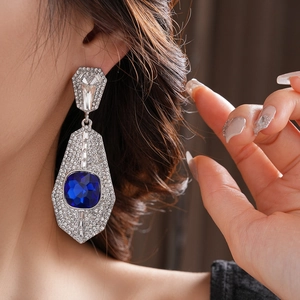 Close-up of oversized Art Deco square earrings with blue gems and micro-set diamonds