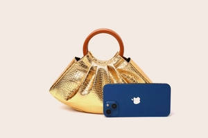 Detail of golden pleated handbag with crocodile pattern and round wooden handle