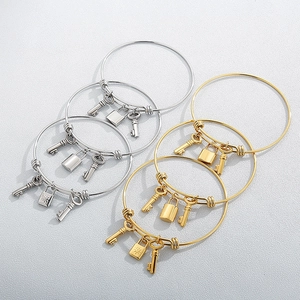 Set of stainless steel bangles with key and lock charms in gold and silver finish