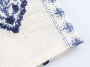 Detailed macro view of blue floral embroidery on white cotton midi sundress fabric
