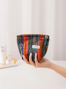 Bohemian rainbow knit makeup bag with floral gold zipper pull and woven label detail