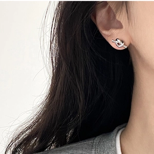 Detailed view of minimalist silver knot earrings worn by a model in a modern style