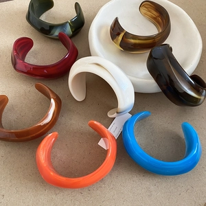 Detailed stack of colorful acrylic cuff bracelets in varied marble textures and solid hues