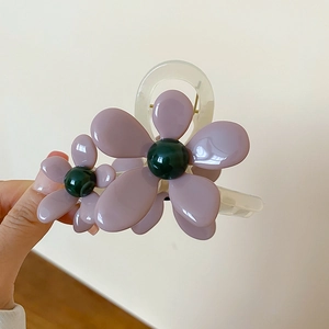 Dettaglio di fermagli per capelli in resina floreale viola e verde scuro traslucida