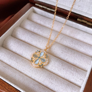 Macro detail of gold flower necklace with blue cat eye stones and pearls in jewelry box
