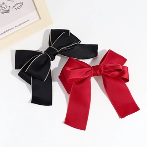 Elegant large satin bow hair clips in black and red colors with a minimalist white backdrop
