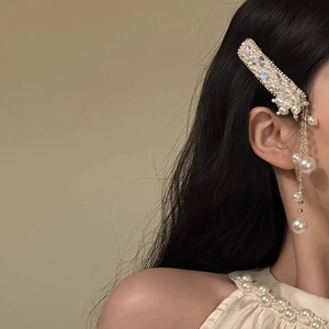 Detail of luxury pearl hair clip with rhinestones and long tassels worn on hair