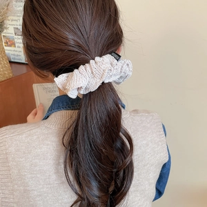 Close-up of a cream knitted scrunchie with FASHION label worn on a ponytail hair