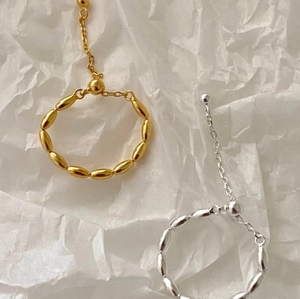 Detailed view of adjustable gold and silver olive bead rings on white textured paper
