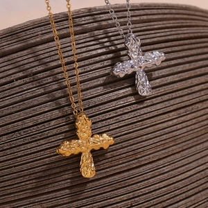 Detail of cross pendants with hammered lava texture in gold and silver finishes