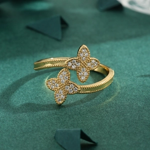 Gold adjustable flower ring with shimmering clover zircon inlay on green background