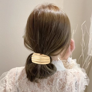 Glossy gold metal ponytail holder with geometric ribbed texture for women's hair