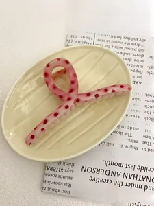 Detail of pink polka dot hair claw clip made of resin on a ceramic tray for hair styling
