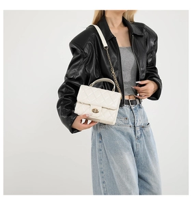 Sac à rabat matelassé blanc avec chaîne dorée et fermoir pivotant porté par un mannequin