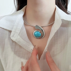 Detail of silver metal choker featuring a swirling turquoise gemstone on a model's neck