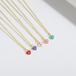 Macro detail of five colorful enamel heart pendants with zircon inlay on gold chains