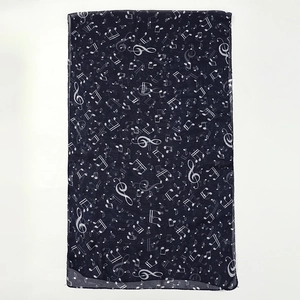 Detailed close-up of chiffon scarf featuring white musical note prints on black fabric