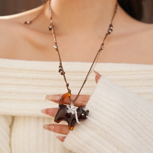 Dettaglio della collana con ciondolo gatto ambra con fiore d'argento e perline intrecciate