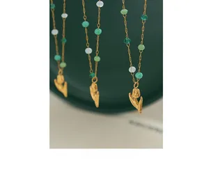 Macro view of gold tulip pendant necklace with green and white crystal beads