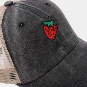 Macro shot of embroidered strawberry patch and breathable mesh on a black baseball cap
