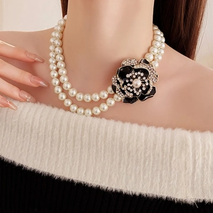 Close-up of double-layer pearl necklace with a rhinestone floral pendant on a model