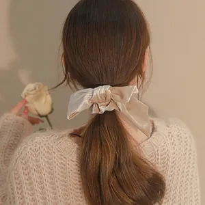 Elegant velvet bow hair tie in champagne gold worn in a low ponytail style