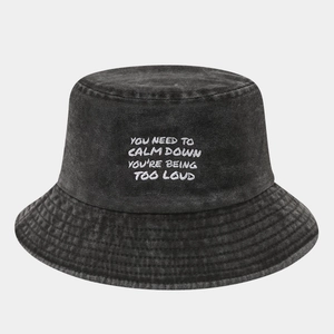 Detailed close-up of dark grey washed denim bucket hat with white embroidered slogan