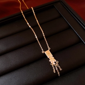 Detail view of 18K gold plated necklace with rectangular diamond pendant and tassels