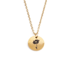 Macro detail of a golden stainless steel pendant featuring a delicate flower etching
