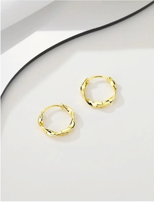 Detailed close-up of golden Mobius twist earrings with bright metallic spiral texture