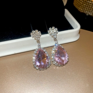Macro detail of teardrop pink zircon earring with silver sparkling diamond accents