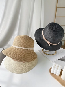 Detailed texture of straw sun hats in black, khaki, and beige with bow accents