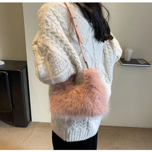 Detail of pink faux fur shoulder bag worn with a white knitted sweater in winter
