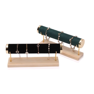 Velvet cylinder jewelry display stand with golden metal support and solid wood base