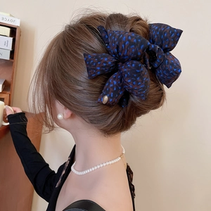 Close-up of a large leopard print fabric bow hair claw clip styled in an elegant bun