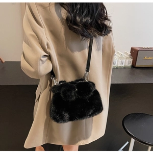 Detail of black plush bunny bucket bag worn with a chic beige blazer on shoulder