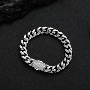 Silver Cuban link bracelet with cubic zirconia spring clasp on black textured rock