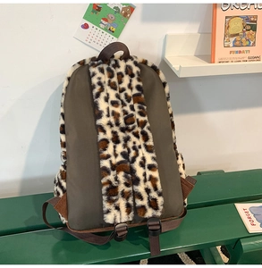 Zaino di peluche marrone con stampa leopardata su una panca verde in stile vintage
