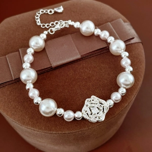 Close-up of pearl bead bracelet with zircon floral charm on brown velvet display
