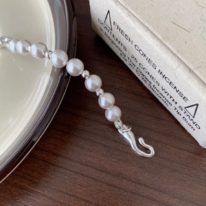 Detail of 925 sterling silver pearl bracelet on a rustic ceramic plate and wood surface