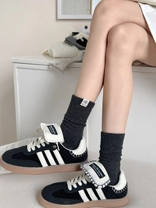 Detail of grey slub knit socks with 'le dog love' label paired with black suede sneakers