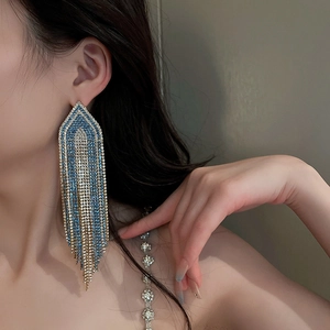 Detail view of long tassel earrings with blue stones and crystals in golden finish